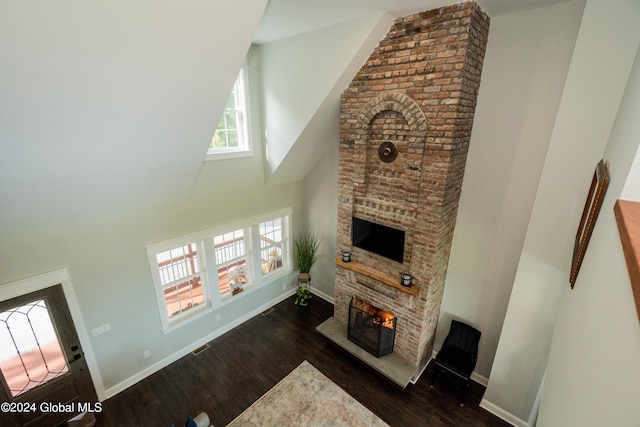 living room with dark wood-type flooring, a large fireplace, and a high ceiling