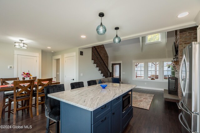 kitchen with a breakfast bar, stainless steel refrigerator, built in microwave, blue cabinets, and dark hardwood / wood-style flooring