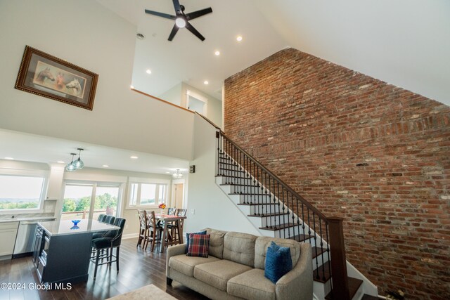 living room featuring high vaulted ceiling, dark hardwood / wood-style floors, ceiling fan, and brick wall