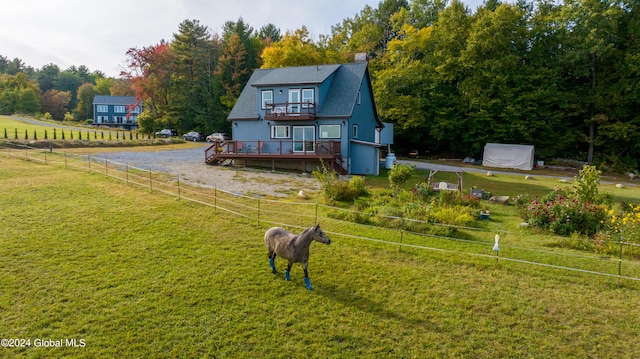 view of front facade featuring a wooden deck, a balcony, a rural view, and a front lawn