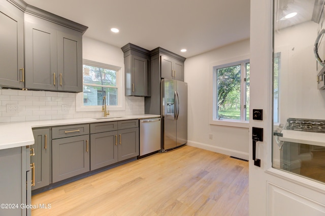 kitchen with appliances with stainless steel finishes, decorative backsplash, sink, and plenty of natural light