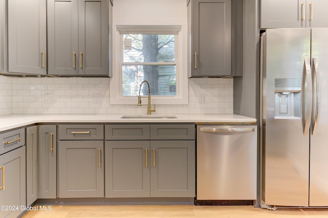 kitchen featuring appliances with stainless steel finishes, sink, tasteful backsplash, and gray cabinetry