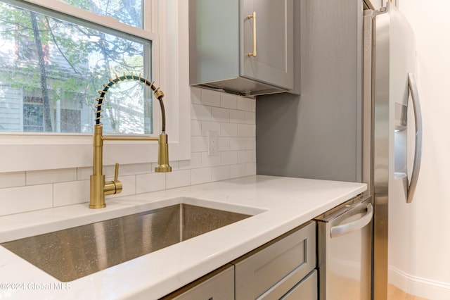 kitchen with decorative backsplash, gray cabinetry, appliances with stainless steel finishes, and sink