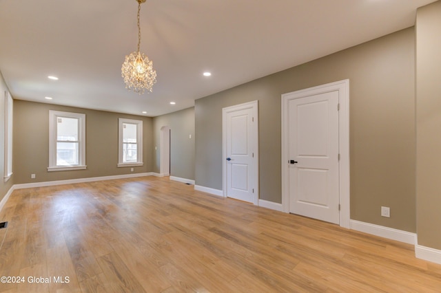 empty room with an inviting chandelier and light hardwood / wood-style flooring