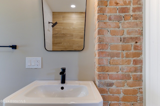 bathroom featuring brick wall and sink