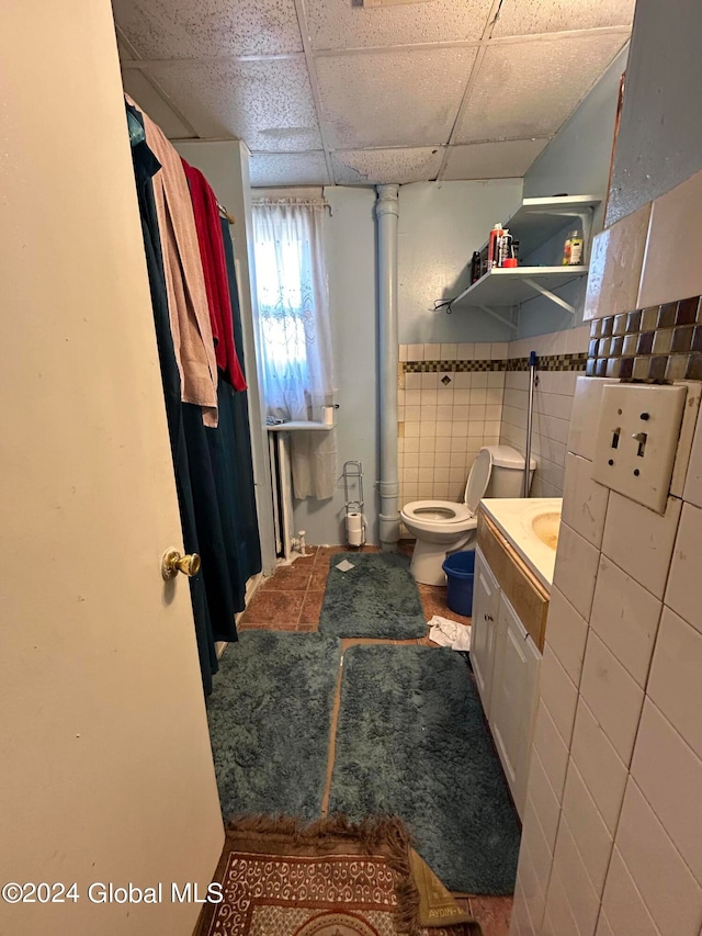 bathroom with vanity, tile walls, a paneled ceiling, and toilet