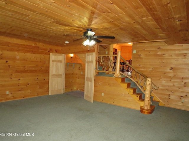 unfurnished living room with wooden ceiling, carpet flooring, wooden walls, and ceiling fan