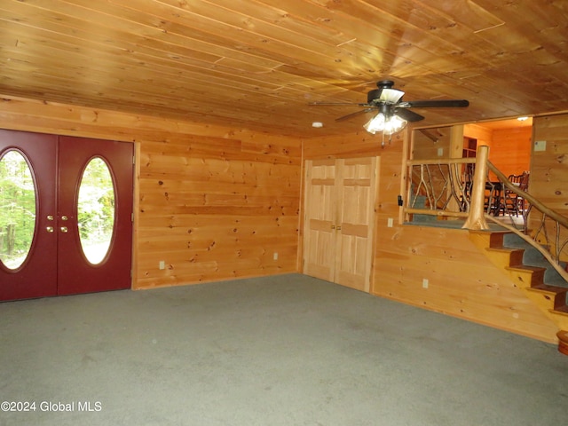 carpeted foyer with ceiling fan, wood ceiling, and wood walls