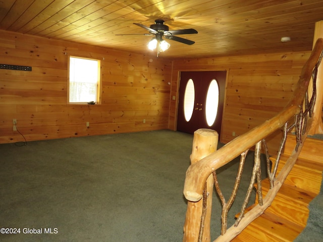 carpeted foyer featuring ceiling fan, wooden walls, and wood ceiling