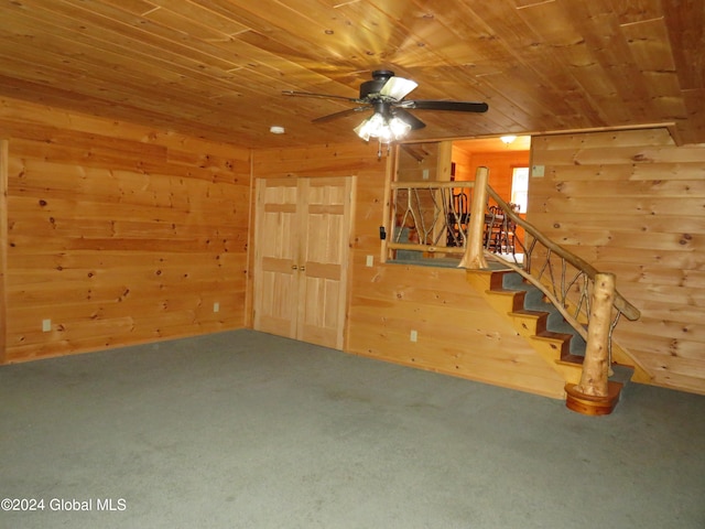 unfurnished living room with wood ceiling, wooden walls, carpet, and ceiling fan