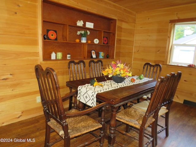 dining space with wooden walls and dark hardwood / wood-style flooring