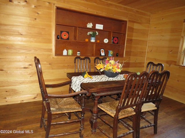 dining room featuring built in features, wood walls, and dark hardwood / wood-style flooring