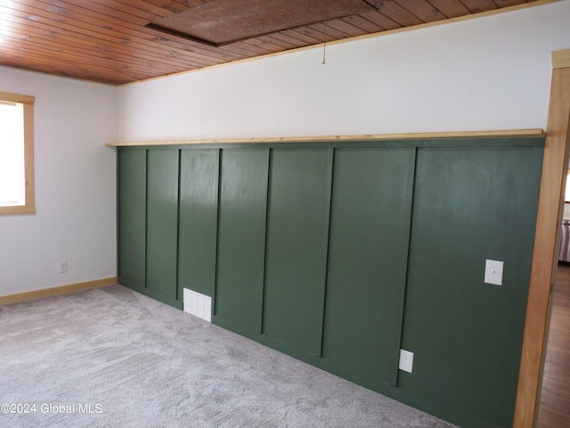 carpeted empty room featuring wooden ceiling