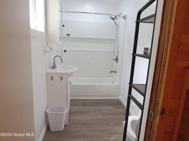 full bathroom featuring washtub / shower combination, wood-type flooring, vanity, and toilet