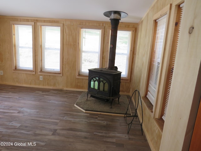 living area with a wood stove, dark wood-type flooring, and wooden walls