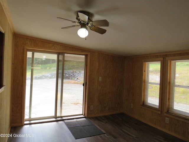 empty room featuring wood walls, dark hardwood / wood-style flooring, and a healthy amount of sunlight