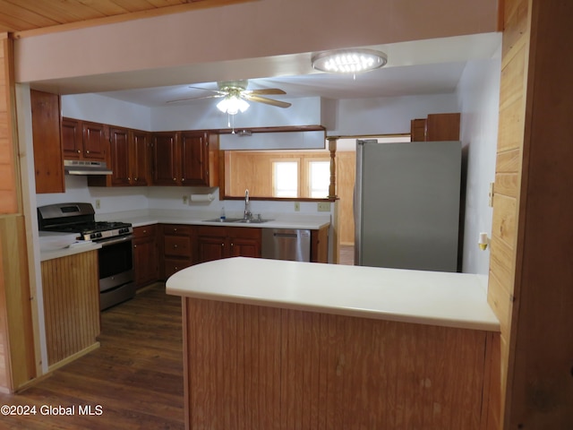 kitchen with appliances with stainless steel finishes, kitchen peninsula, dark hardwood / wood-style flooring, ceiling fan, and sink