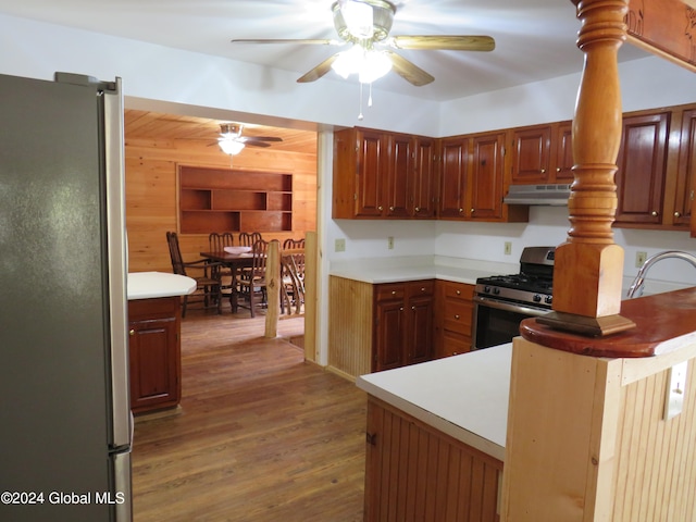 kitchen featuring appliances with stainless steel finishes, wooden walls, dark hardwood / wood-style flooring, and ceiling fan