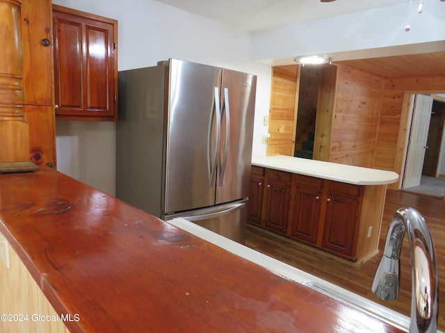 kitchen featuring stainless steel refrigerator, wooden walls, and dark wood-type flooring