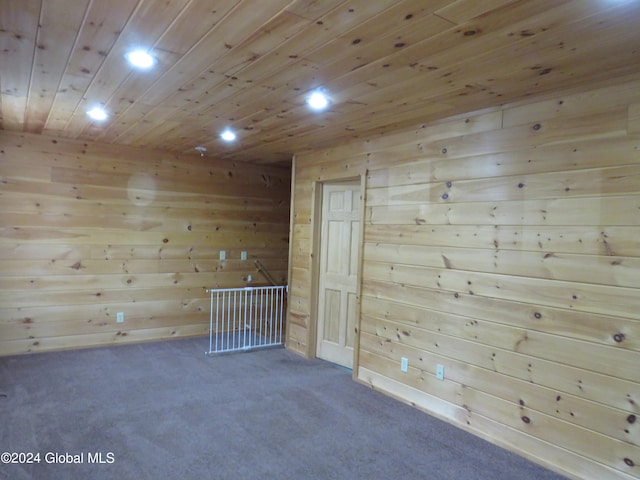 carpeted spare room featuring wood ceiling and wood walls