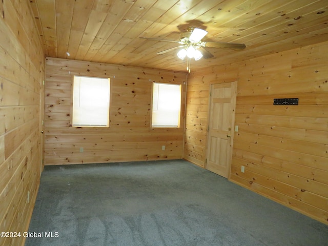 carpeted spare room with wooden ceiling, wooden walls, and ceiling fan