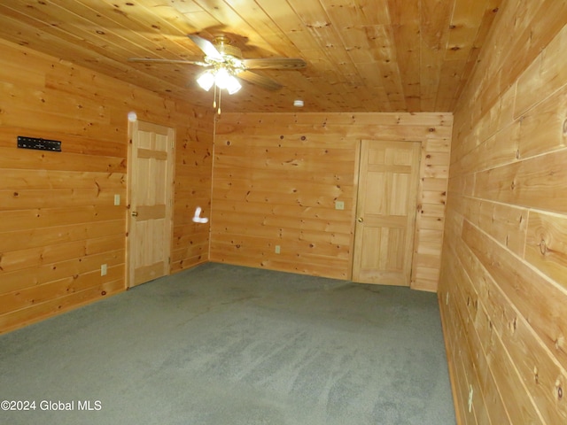 spare room featuring wood ceiling, wood walls, ceiling fan, and carpet