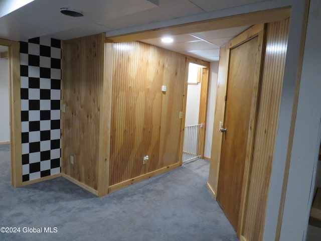 corridor featuring wooden walls and carpet flooring