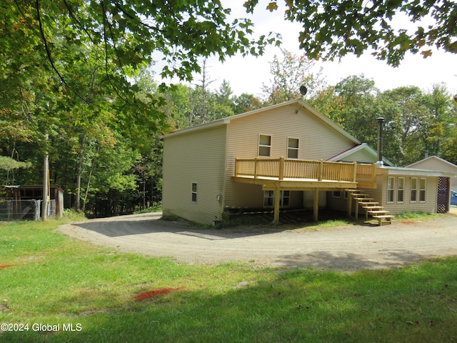 back of property with a lawn and a wooden deck