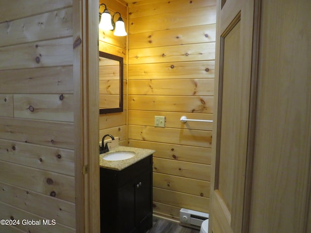 bathroom with wood walls, baseboard heating, vanity, hardwood / wood-style floors, and toilet