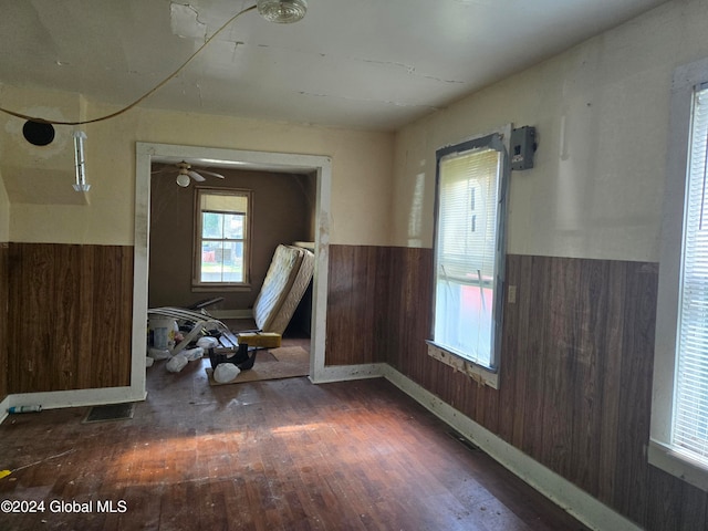 unfurnished room featuring ceiling fan, dark hardwood / wood-style floors, and wood walls