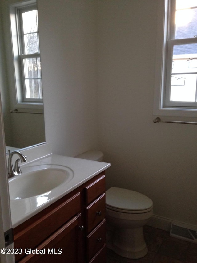 bathroom with a wealth of natural light, tile patterned floors, vanity, and toilet