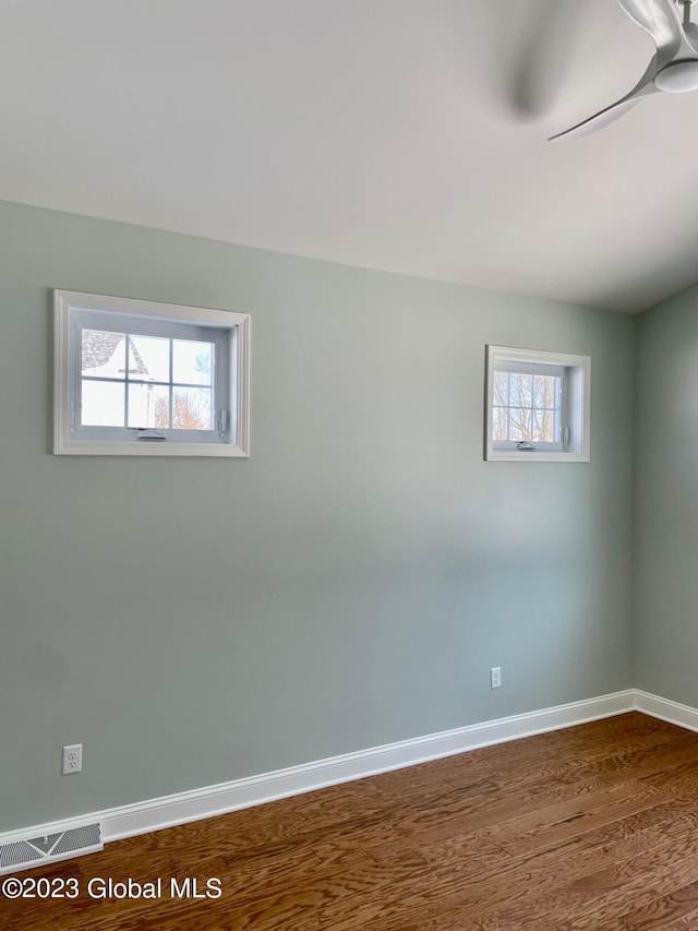 spare room featuring ceiling fan, hardwood / wood-style floors, and a healthy amount of sunlight