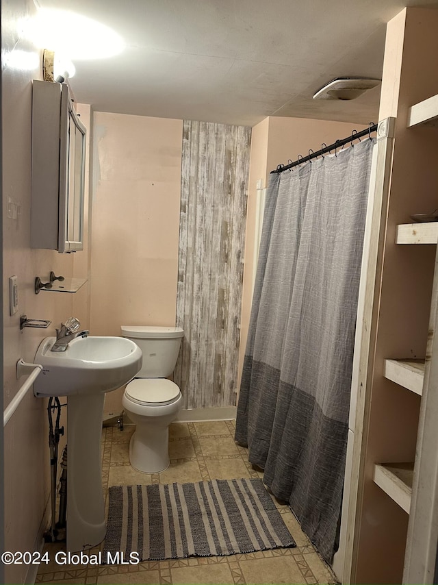 bathroom featuring tile patterned flooring, toilet, and curtained shower