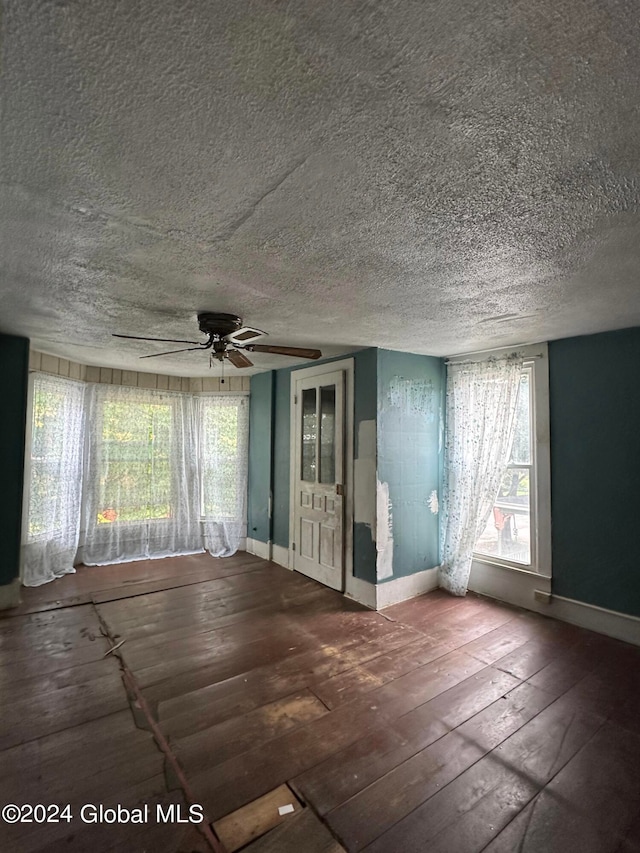 unfurnished room featuring a textured ceiling, a healthy amount of sunlight, hardwood / wood-style floors, and ceiling fan