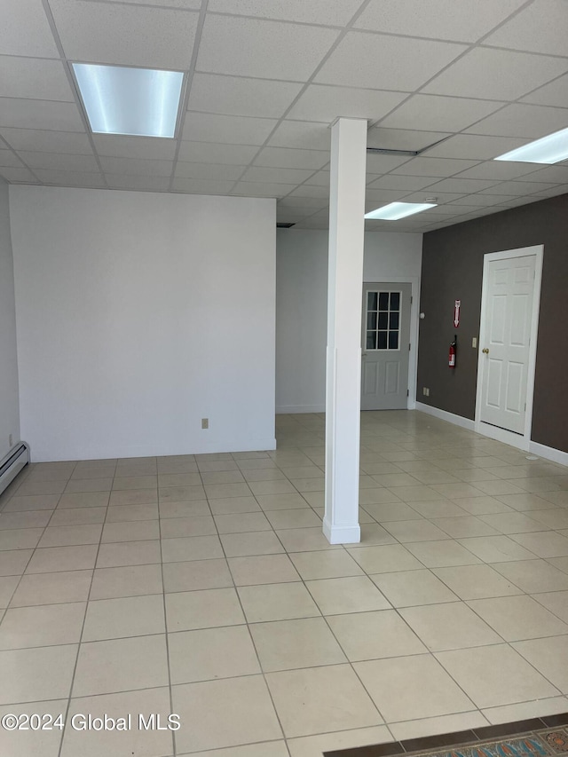 basement featuring a drop ceiling and light tile patterned floors