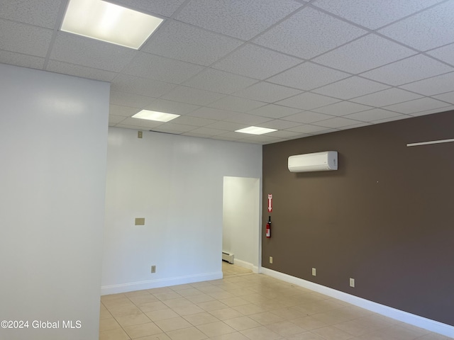 spare room featuring an AC wall unit, baseboard heating, light tile patterned floors, and a paneled ceiling