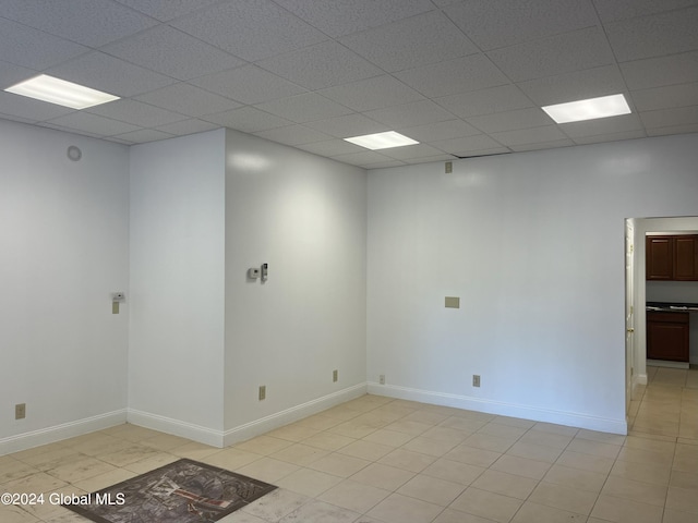 empty room featuring a paneled ceiling and light tile patterned floors