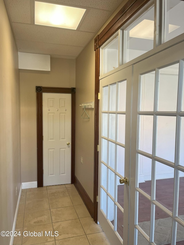 doorway with french doors, light tile patterned flooring, and a paneled ceiling