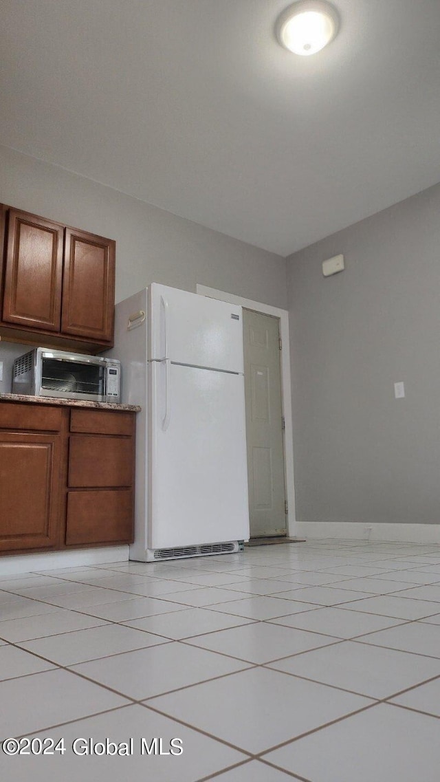 kitchen with light tile patterned floors and white fridge