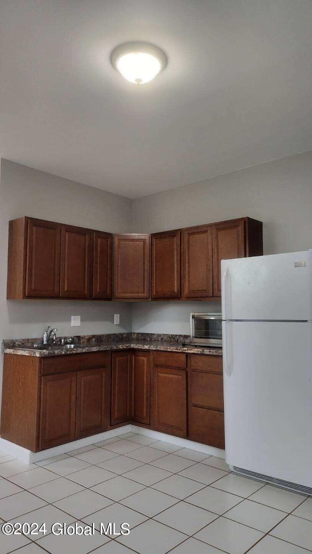 kitchen with white refrigerator, light tile patterned flooring, and sink