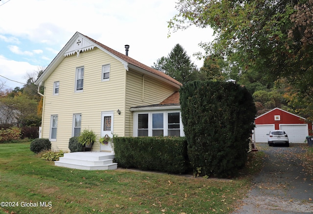 view of front of home featuring an outdoor structure, a garage, and a front lawn