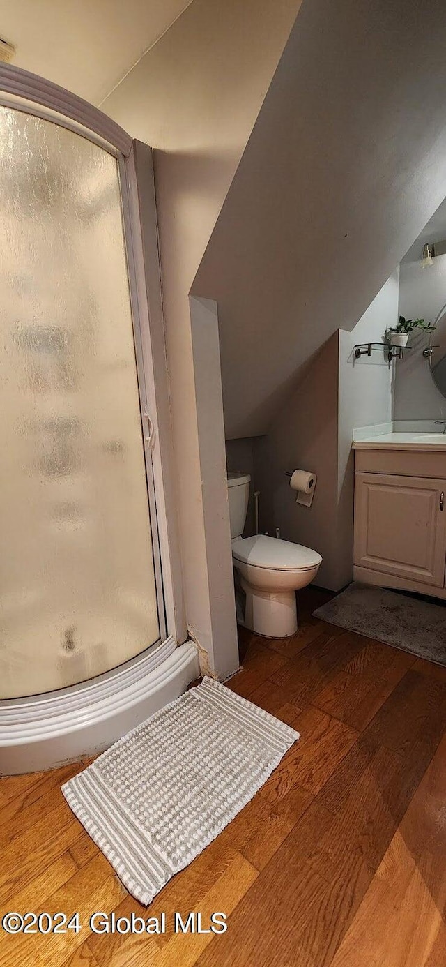 bathroom featuring a shower with door, wood-type flooring, lofted ceiling, and toilet