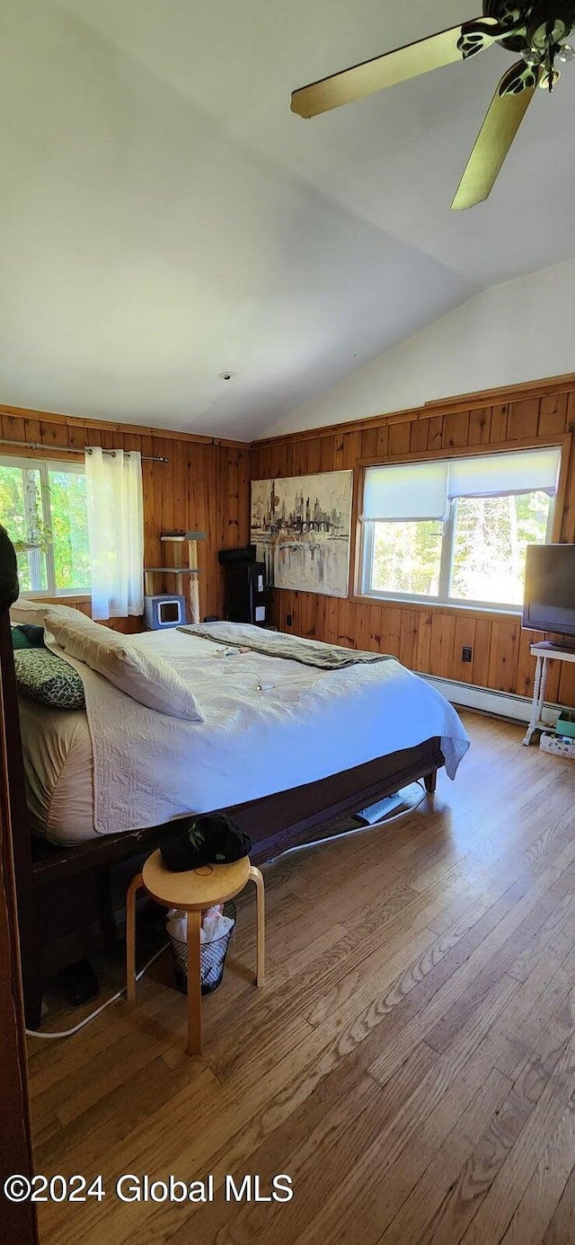 bedroom featuring ceiling fan, wooden walls, vaulted ceiling, and hardwood / wood-style flooring