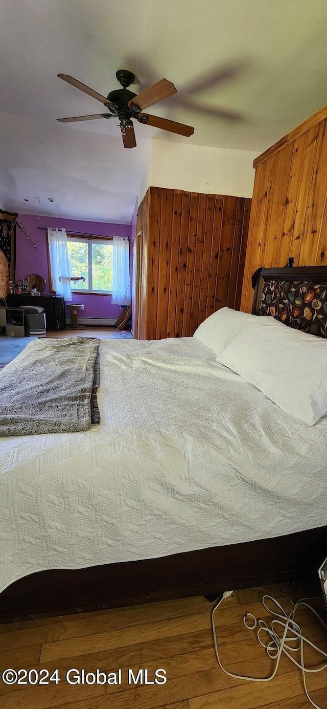 bedroom featuring hardwood / wood-style flooring, ceiling fan, wooden walls, and vaulted ceiling