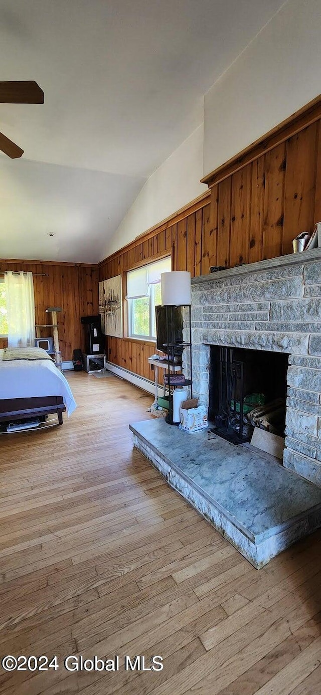 interior space featuring light hardwood / wood-style floors, a fireplace, wooden walls, and vaulted ceiling