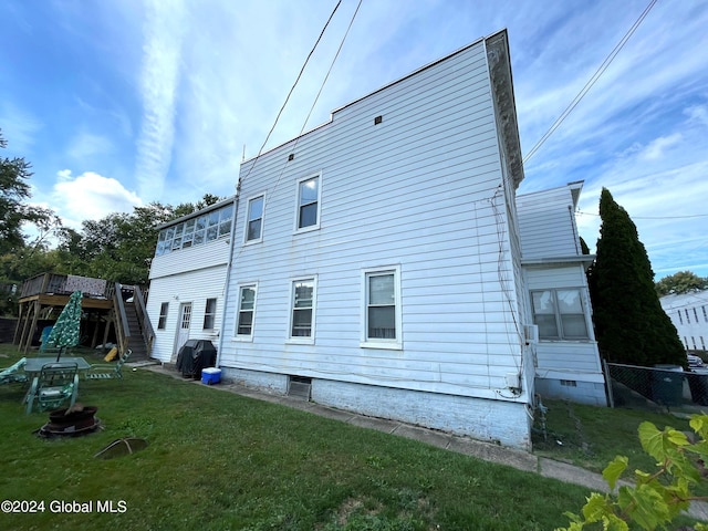 back of property with a lawn and a wooden deck