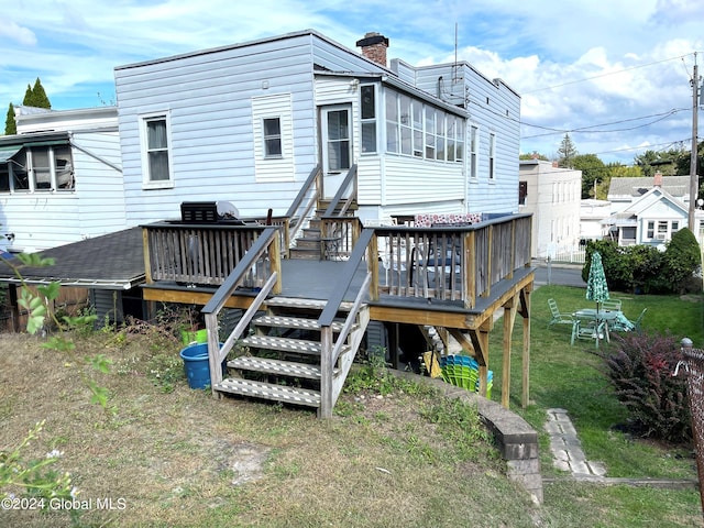 back of property featuring a wooden deck and a lawn