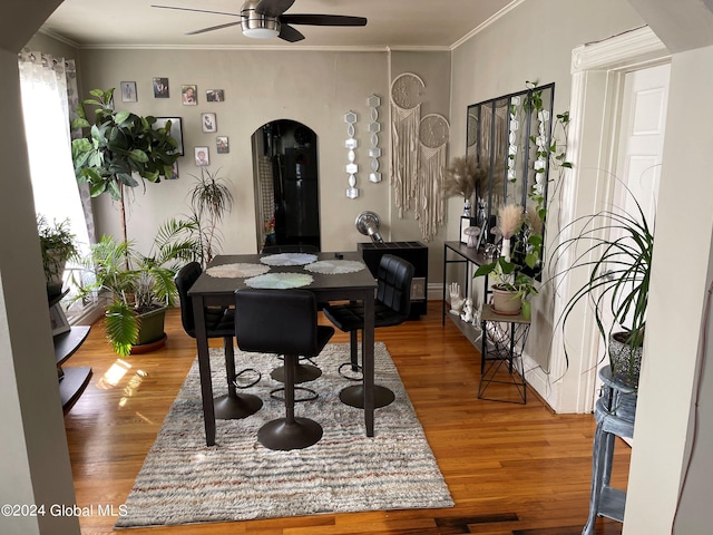 dining area with wood-type flooring, crown molding, and ceiling fan