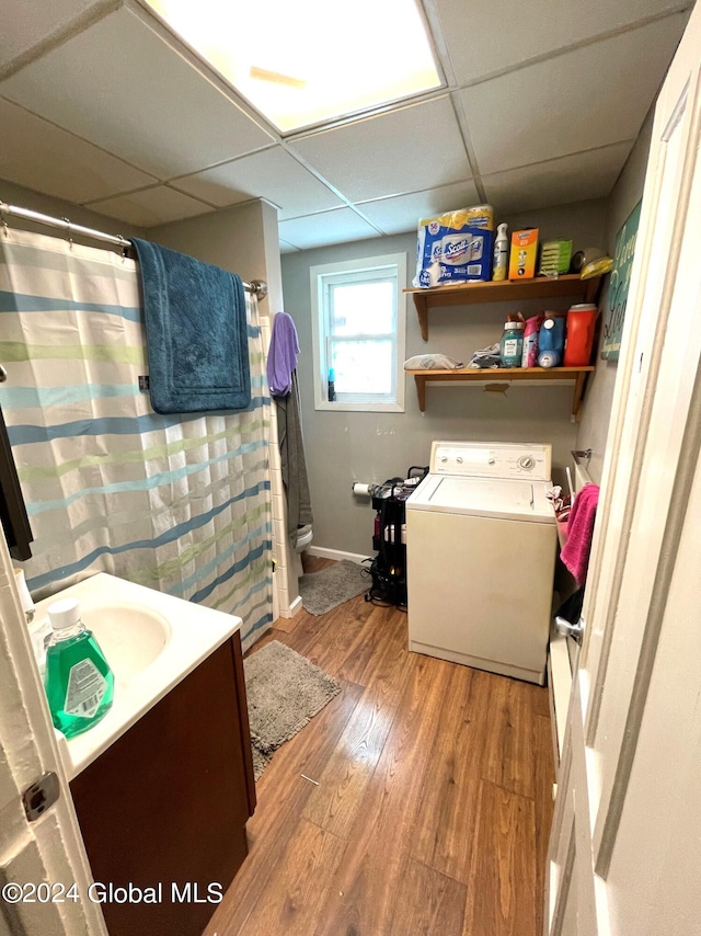 bathroom featuring washer / clothes dryer, a drop ceiling, hardwood / wood-style floors, vanity, and toilet