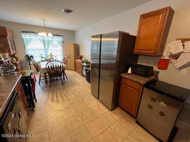 kitchen featuring hanging light fixtures, stainless steel refrigerator, dishwasher, and a notable chandelier